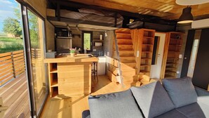 Ein kompakter Wohnraum mit einer Küchenzeile, einer Holztreppe und einem Sofa.