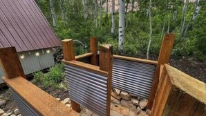 A wooden deck with a metal railing, surrounded by a stone pathway and birch trees. - Sunflower Lodge Near Park City (Silver Summit)