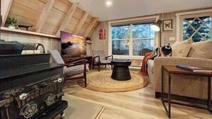 A living room with a piano, a sofa, a coffee table, and a large window with a view of trees. - Sunflower Lodge Near Park City (Silver Summit)