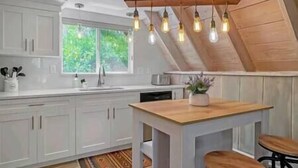 A kitchen with white cabinets, a wooden countertop, and a hanging light fixture. - Sunflower Lodge Near Park City (Silver Summit)