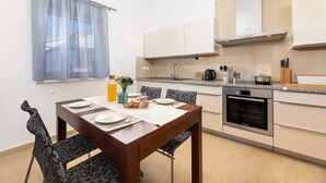 Une cuisine moderne équipée d’un four Bosch, d’une table à manger avec des chaises et d’une fenêtre avec un rideau.