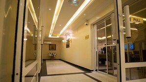 Een hotel lobby met een lange gang, een receptie en een glazen deur met een 'PULL'-bord.