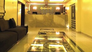 Een hotel lobby met een receptiebalie, een bank en een glazen bijzettafeltje.