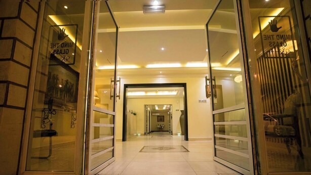 Een hotelingang met glazen deuren, een betegelde vloer en een goed verlicht interieur.