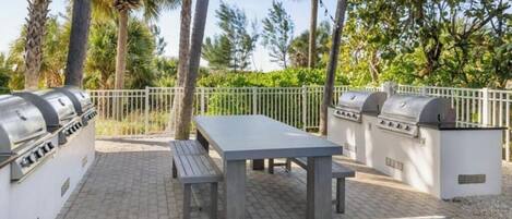 An outdoor patio with a grill station, a table, and benches.