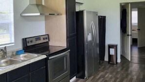 A modern kitchen with stainless steel appliances, a wooden cabinet, and a herringbone wood floor. - Peaceful and Private Cabin with fun activities for family & friends on 25 Acres (Broaddus)