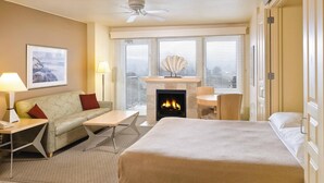 A hotel room with a bed, a sofa, a small table, a fireplace, and a window with blinds. - 2-bedroom beachfront condo in Seaside with free WiFi, kitchen, and pool. (Seaside)