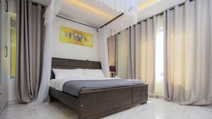 Un dormitorio moderno con una cama grande, una lámpara de techo y un cuadro en la pared.