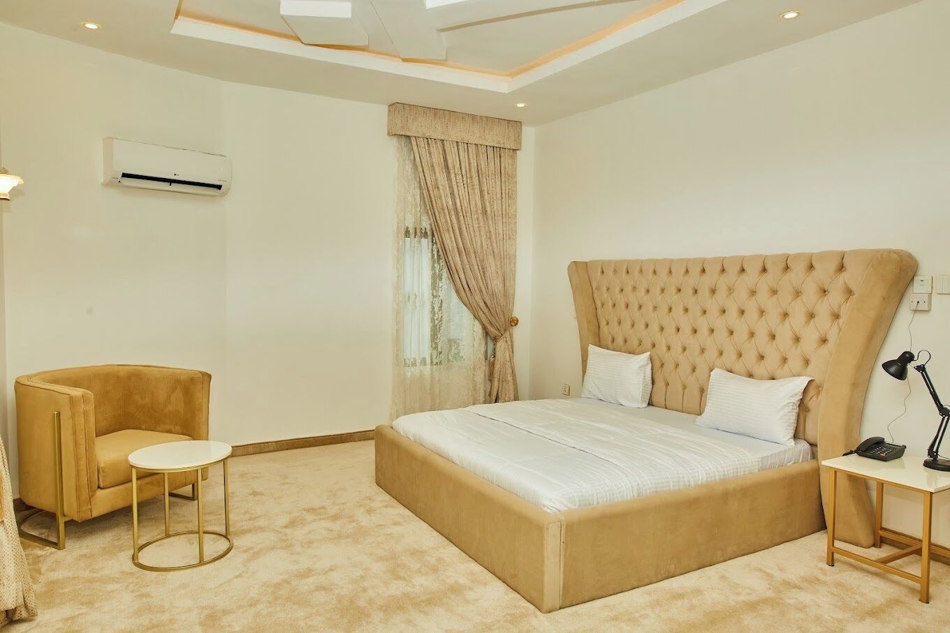 A bedroom with a large bed, a chair, a small table, and a bedside lamp.