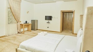 A hotel room with a bed, a desk, a television, and a wardrobe. - BILAD AL-SHAM HOTEL AND SUITES (Kano)