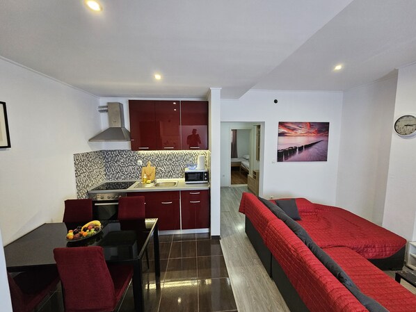 A compact living space with a kitchenette, a dining area, and a seating area with a red sofa.