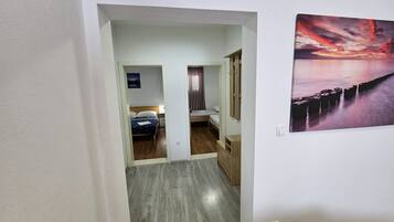 A hallway with a bed, a desk, and a painting on the wall.