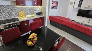 Una cucina moderna con un piano di lavoro nero, mobili rossi e una ciotola di frutta.