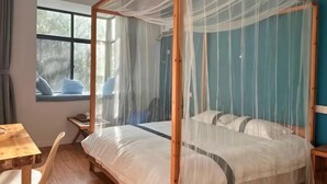 A four-poster bed with a canopy, a wooden desk, a chair, and a window with curtains. - Ting San Rice Fields & Yard (Xuancheng)