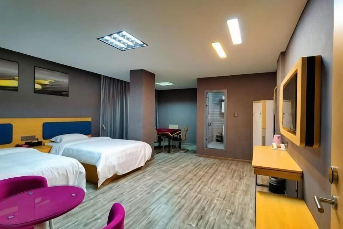 Une chambre d’hôtel avec deux lits, un bureau, une chaise et une petite table.