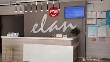A reception desk with a modern design, a digital screen, and informational posters on the wall.