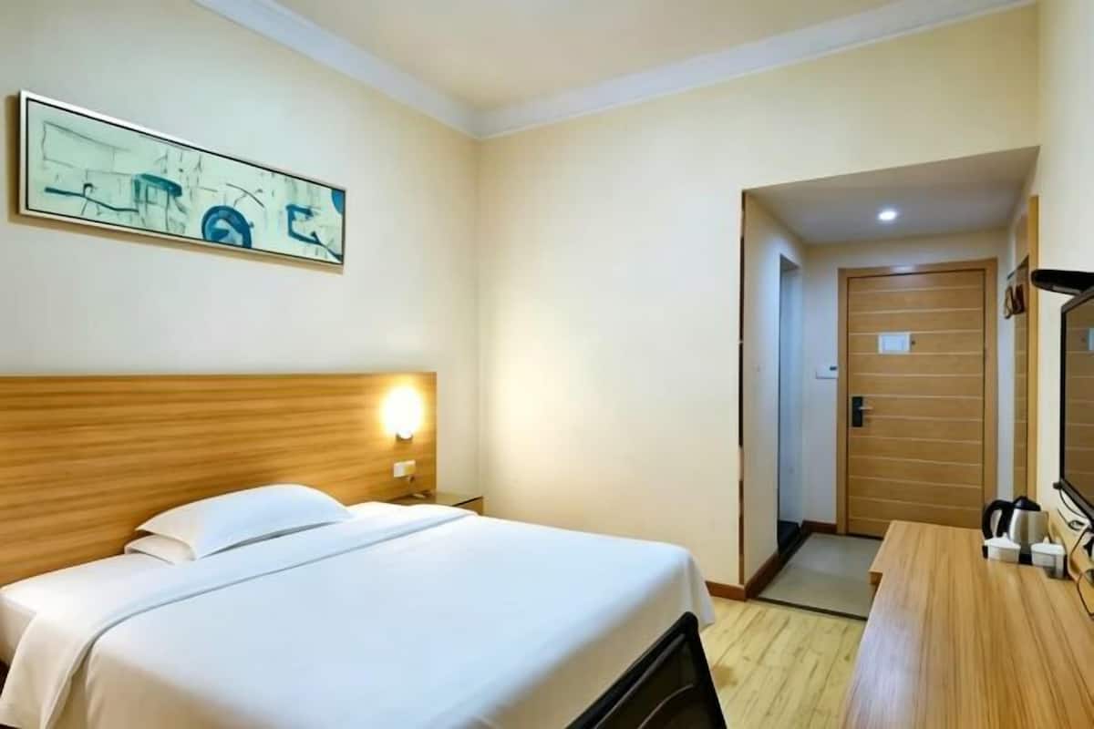 Une chambre d’hôtel avec un lit, une table de chevet, une lampe et un tableau au mur.