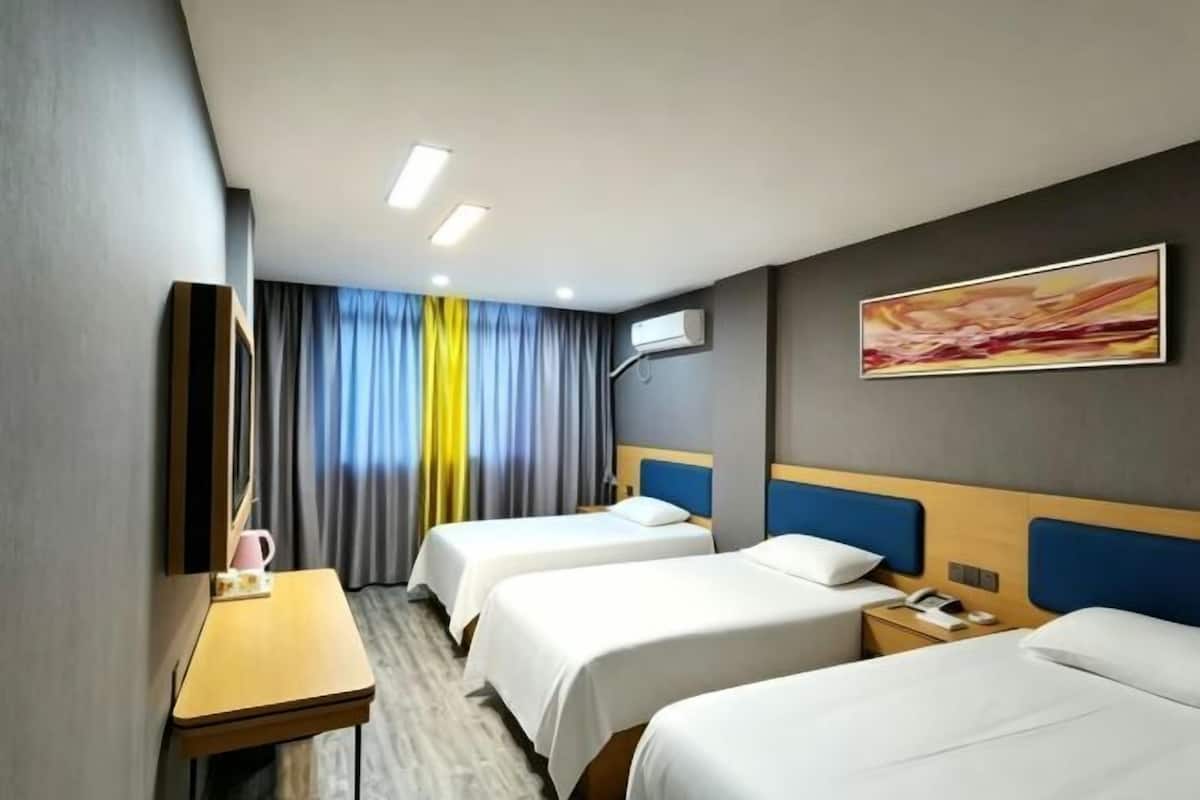 Une chambre d’hôtel avec deux lits, un bureau, un miroir et une fenêtre avec des rideaux.