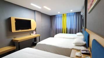 Een hotelkamer met twee bedden, een tv aan de muur, een bureau met stoel en een raam met gordijnen.