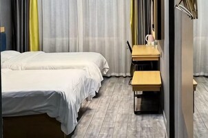Habitación de hotel con dos camas, un escritorio con una silla y un espejo.