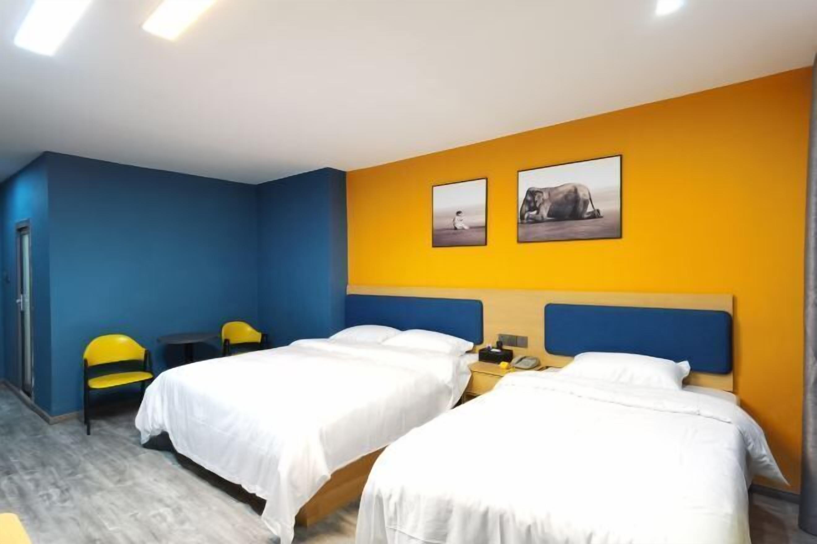 Een hotelkamer met twee bedden, een nachtkastje, een stoel en kunst aan de muur.