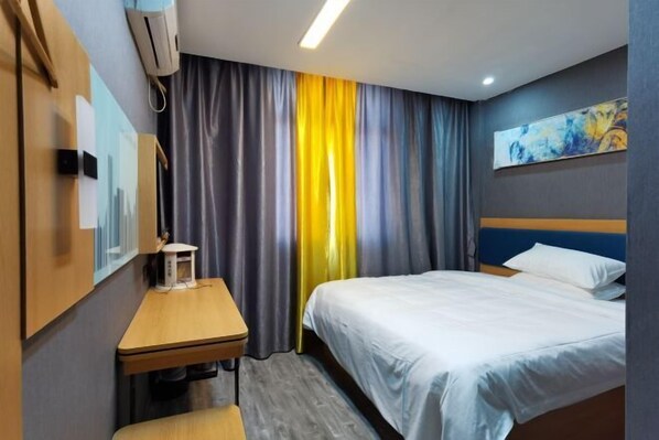 Hotelkamer met een bed, een bureau, een stoel, een wandairconditioner en een schilderij.