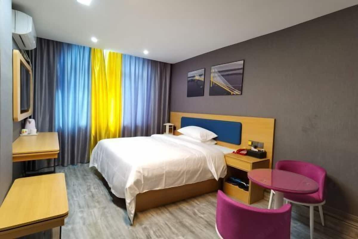 Une chambre d’hôtel avec un lit, un bureau, une chaise et une petite table.