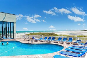 Ein Pool mit Liegestühlen und Blick auf den Strand.
