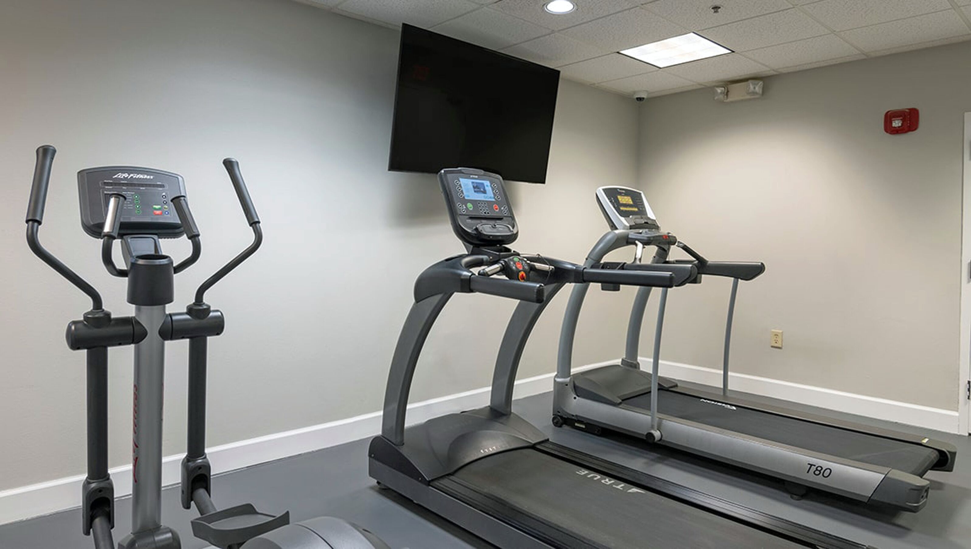 A gym with two elliptical machines and a treadmill.