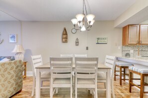 Ein Essbereich mit einem weißen Tisch und Stühlen, einer Chandelier und einer Küche mit Holzschränken.