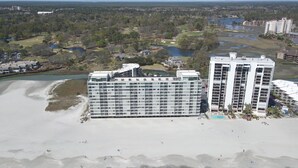 A beachfront hotel with multiple floors, a pool, and a beach area.