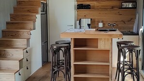 Una cucina moderna con isola centrale, scala in legno e sgabelli da bar.