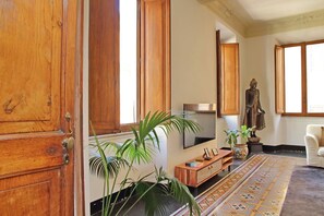 A room with a wooden door, a large mirror, a statue, a potted plant, and a patterned rug.