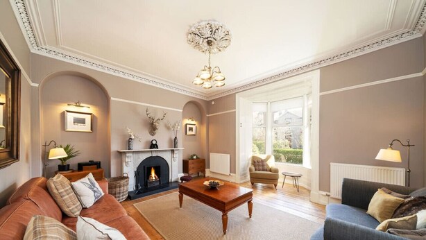 A living room with a fireplace, two sofas, a coffee table, and a chandelier. - Fountainhall Townhouse, Aberdeen (Aberdeen City)