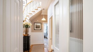 A hallway with a wooden staircase, a vase of flowers, and a framed picture on the wall. - Fountainhall Townhouse, Aberdeen (Aberdeen City)