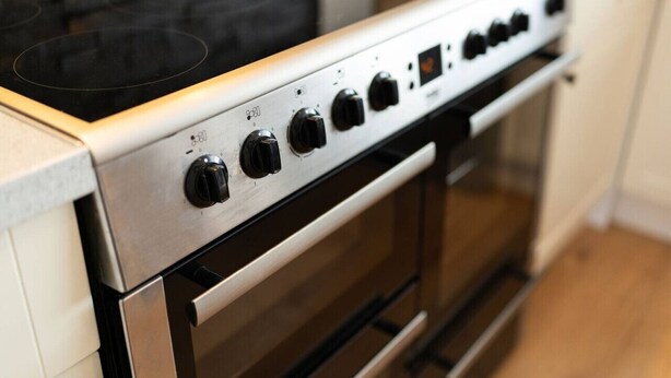 Une cuisine moderne dotée d’une hotte en acier inoxydable, d’un four encastré et d’une plaque de cuisson.