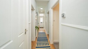 A narrow hallway with white walls and a patterned blue and beige carpet.