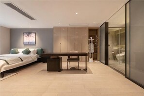 A modern bedroom with a bed, bedside table, chair, and a glass-enclosed bathroom. - Cres&Asia Residence (Chengdu)