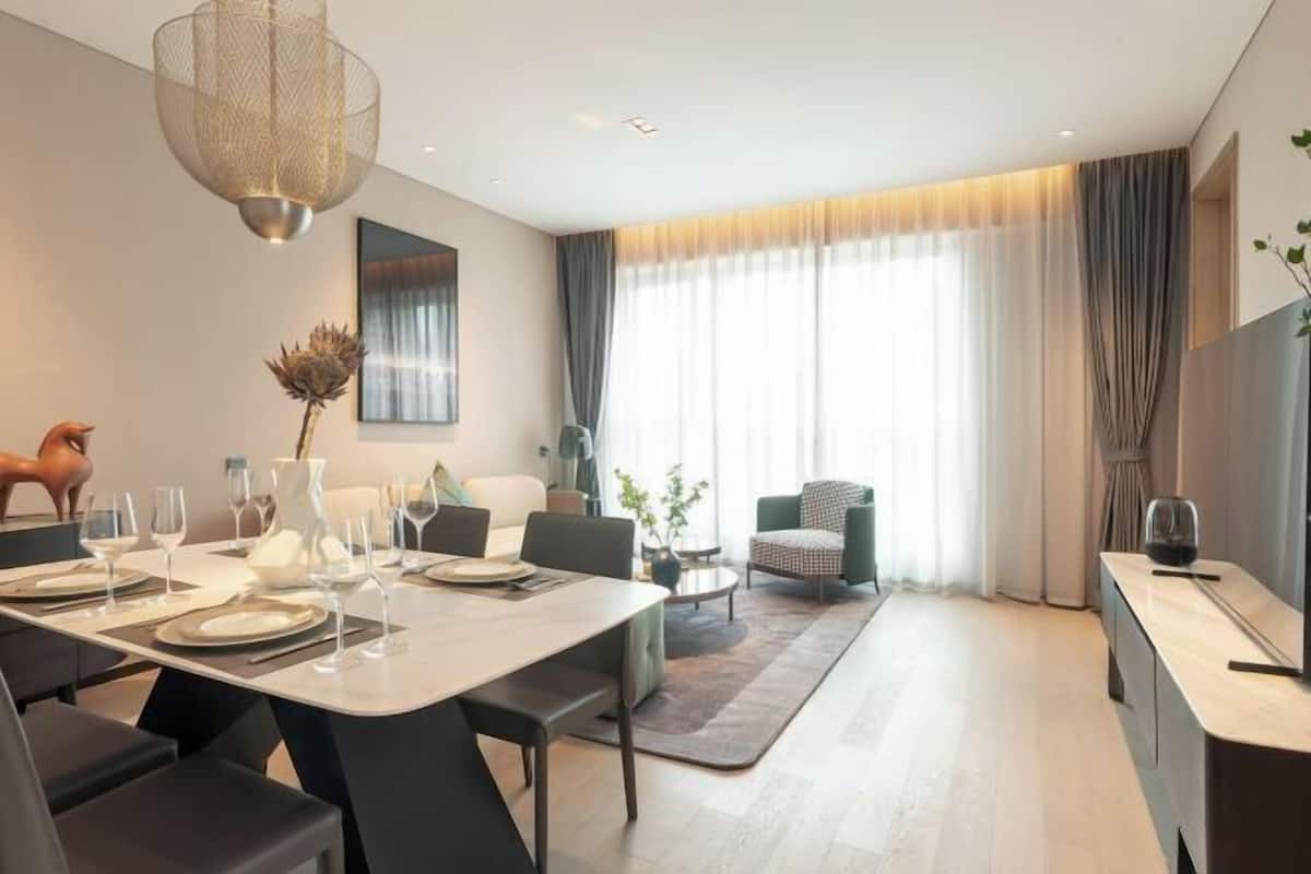 A modern dining area with a long table set for six, a sofa, and a chair in the background.