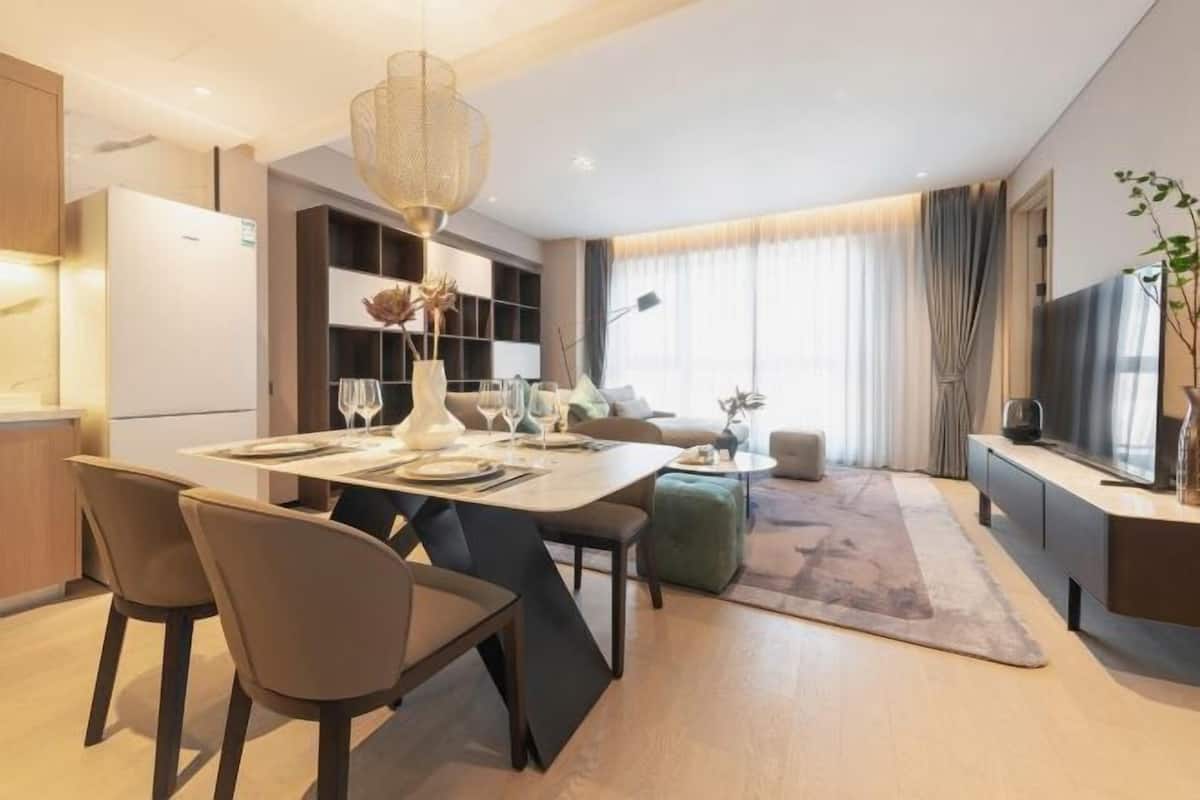 A modern living room with a dining area, a sofa, a TV, and a large window with curtains.