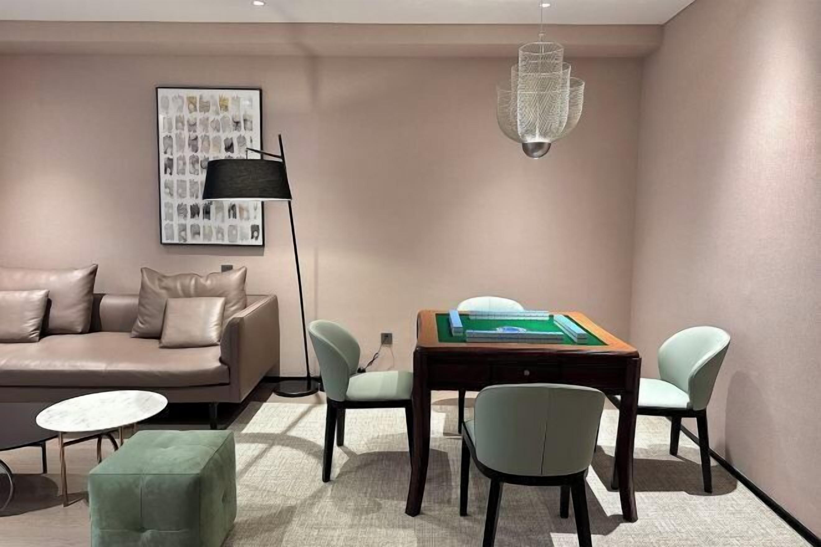 A modern living room with a sofa, a coffee table, a dining table with chairs, a floor lamp, and a chandelier.