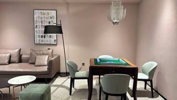 A modern living room with a sofa, a coffee table, a dining table with chairs, a floor lamp, and a chandelier.
