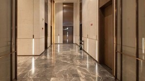 Un pasillo con suelo de mármol y puertas de vidrio a ambos lados.