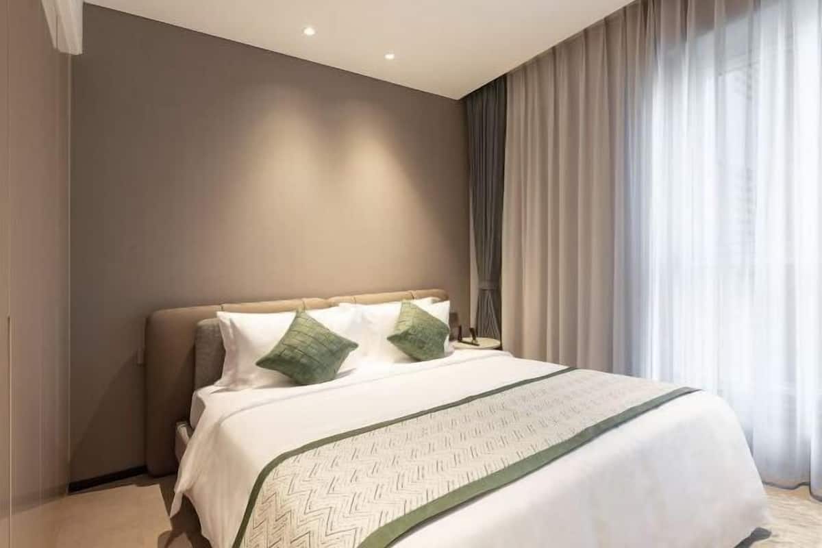 A neatly made bed with a patterned bedspread, a headboard, and two pillows.