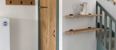 Ein Zimmer mit Holztür, einem weißen Kühlschrank und einer Treppe mit blauer Handlauf.