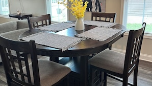A dining area with a round table, dark wooden chairs, and a vase with yellow flowers.