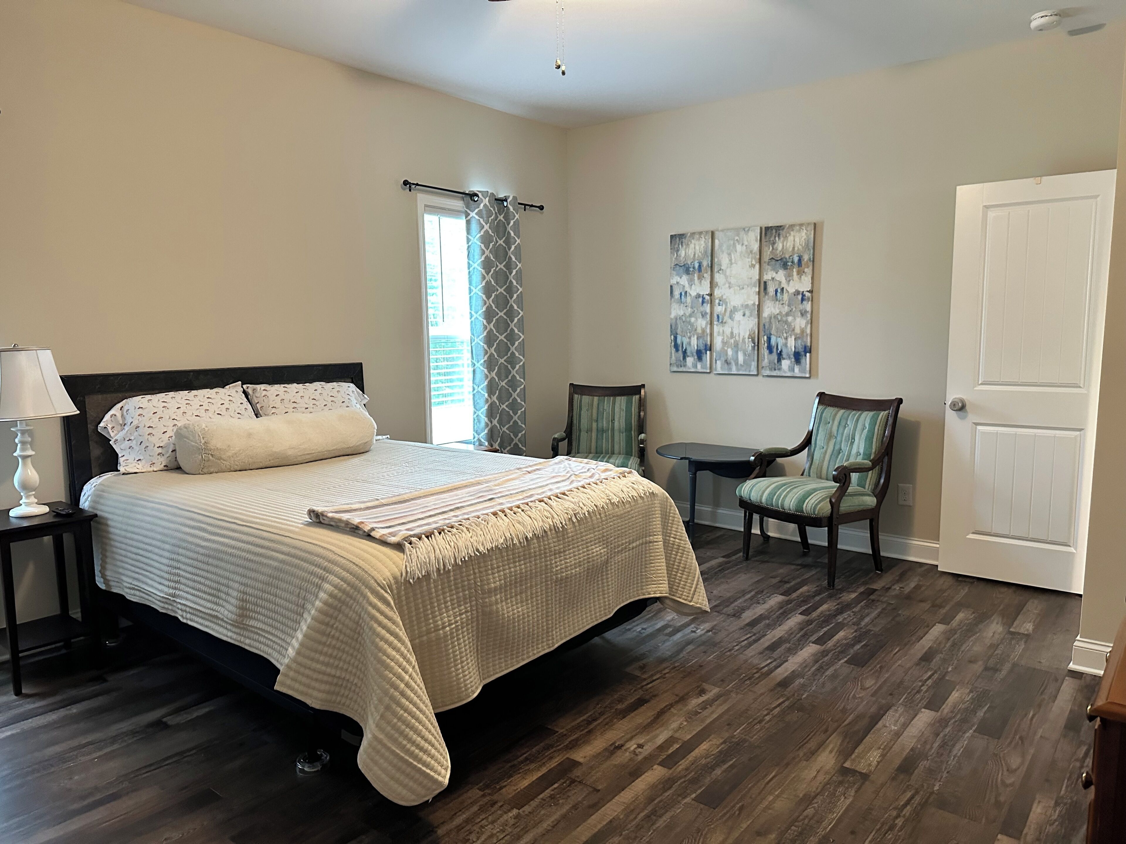 Une chambre à coucher avec un lit, une table de chevet, une chaise, une petite table et une porte.