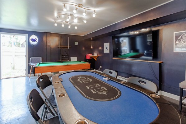 A pool table with a blue felt surface and a chalkboard design, surrounded by chairs and a pool table with a green felt surface. - Game day house, walkable to campus (State College)