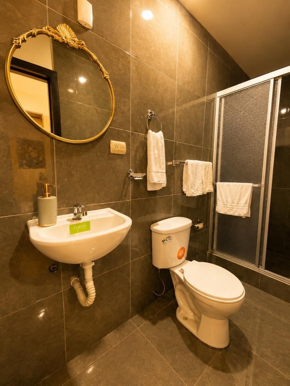 Un baño con lavamanos, inodoro y zona de ducha.