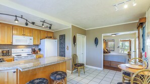 Una cucina con mobili in legno, un forno a microonde e un frigorifero. C'è una zona pranzo con tavolo e sedie.